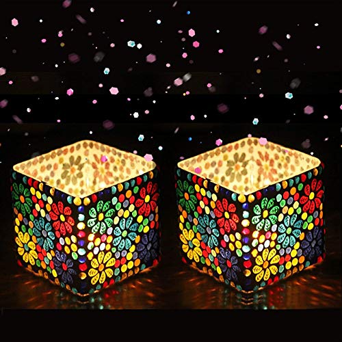 Two colorful mosaic candle holders on a dark background with confetti.
