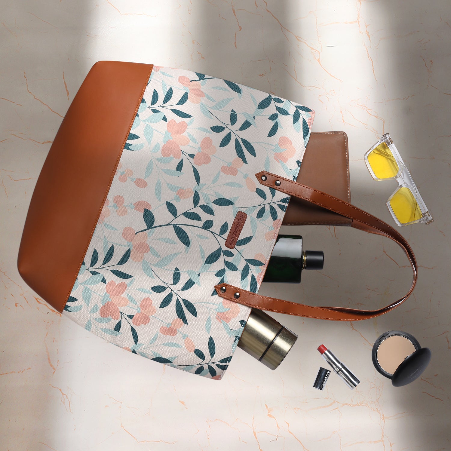 Chic tote bag adorned with floral pattern and brown leather handle, a trendy accessory.
