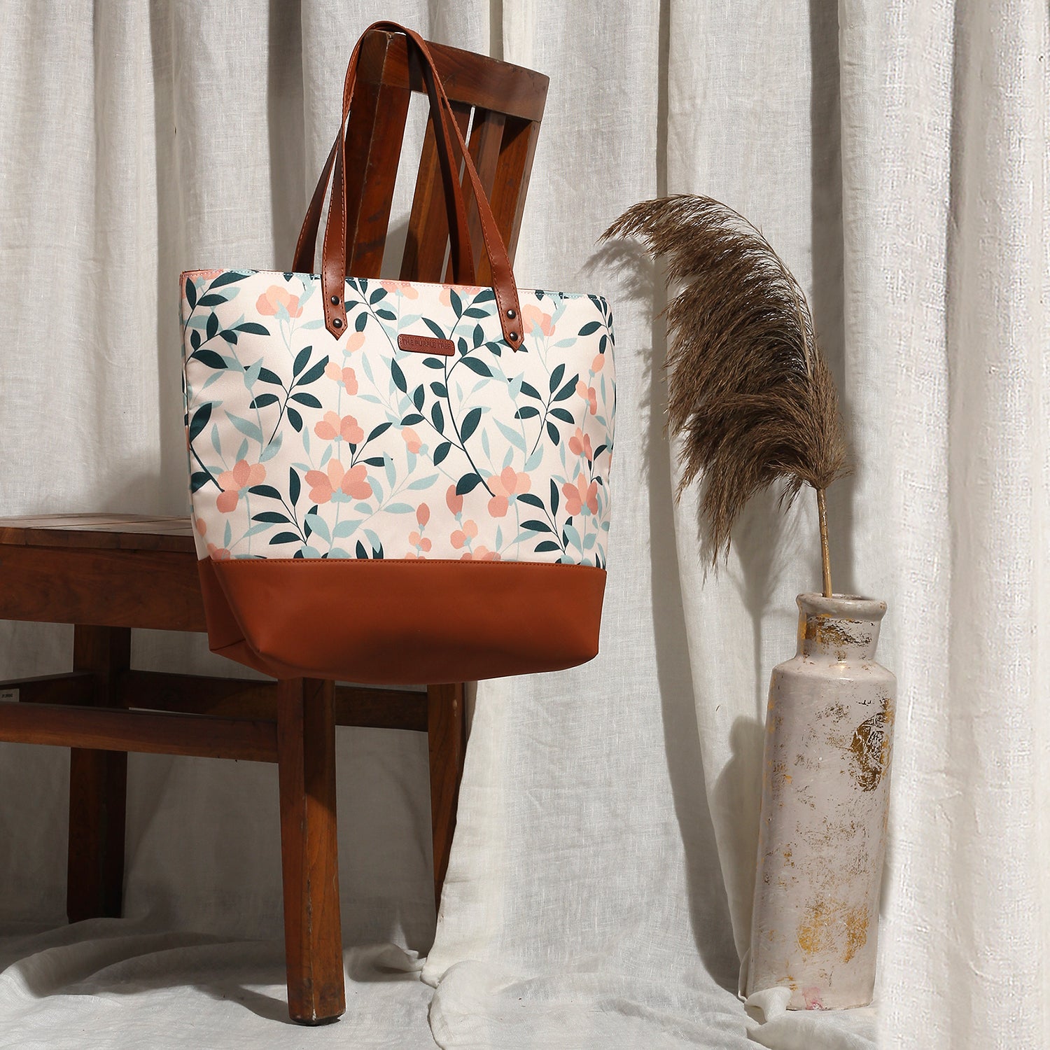 Fashionable tote bag with floral design and brown leather handle, ideal for everyday use.