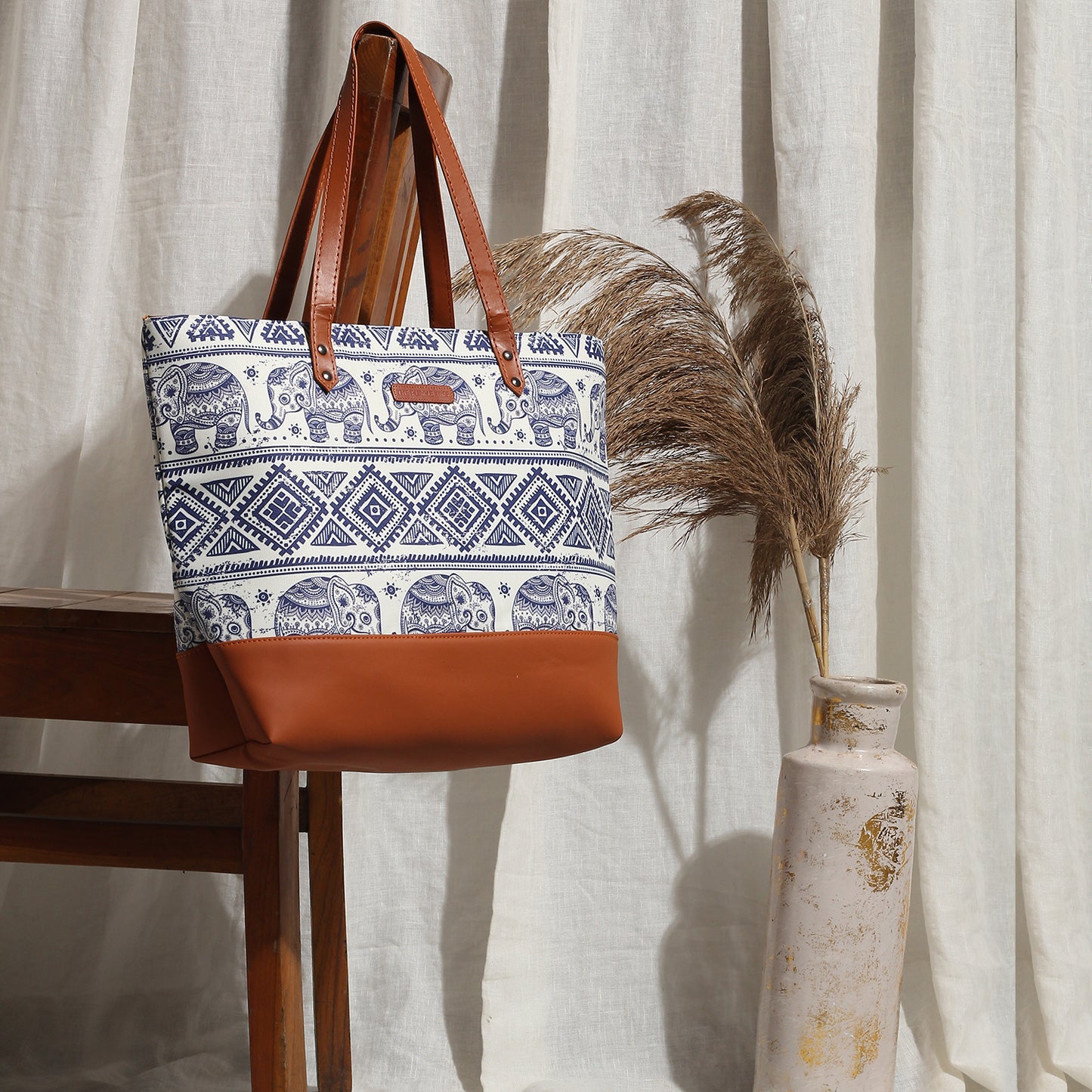 Trendy tote bag made of leather with elephant print and brown handle.