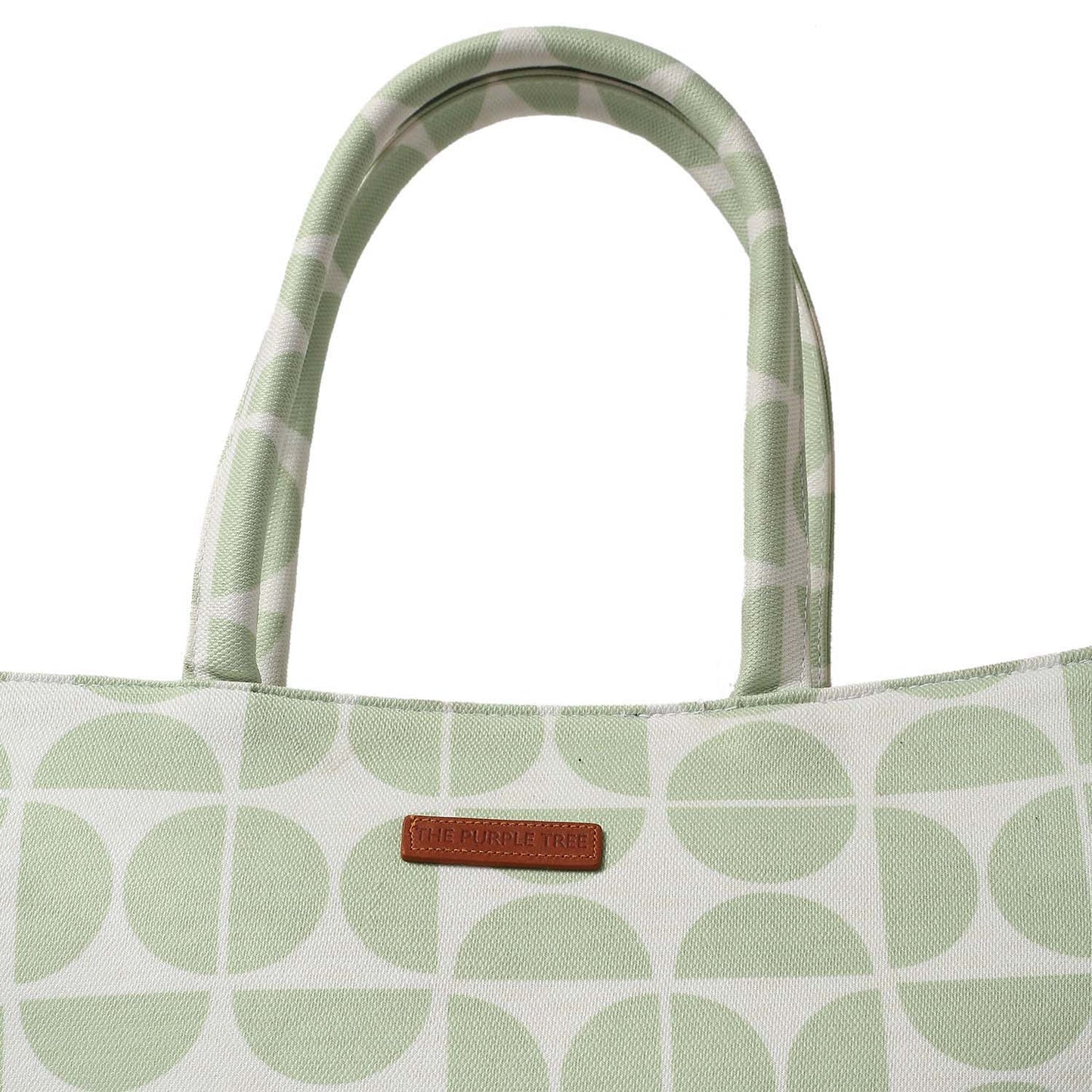Tote bag in green and white with book and notebook on table.
