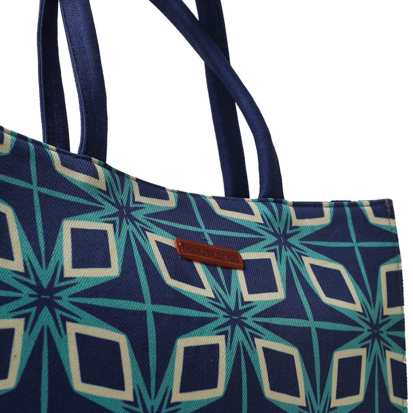 A vibrant tote bag featuring a blue and green pattern, alongside two books.