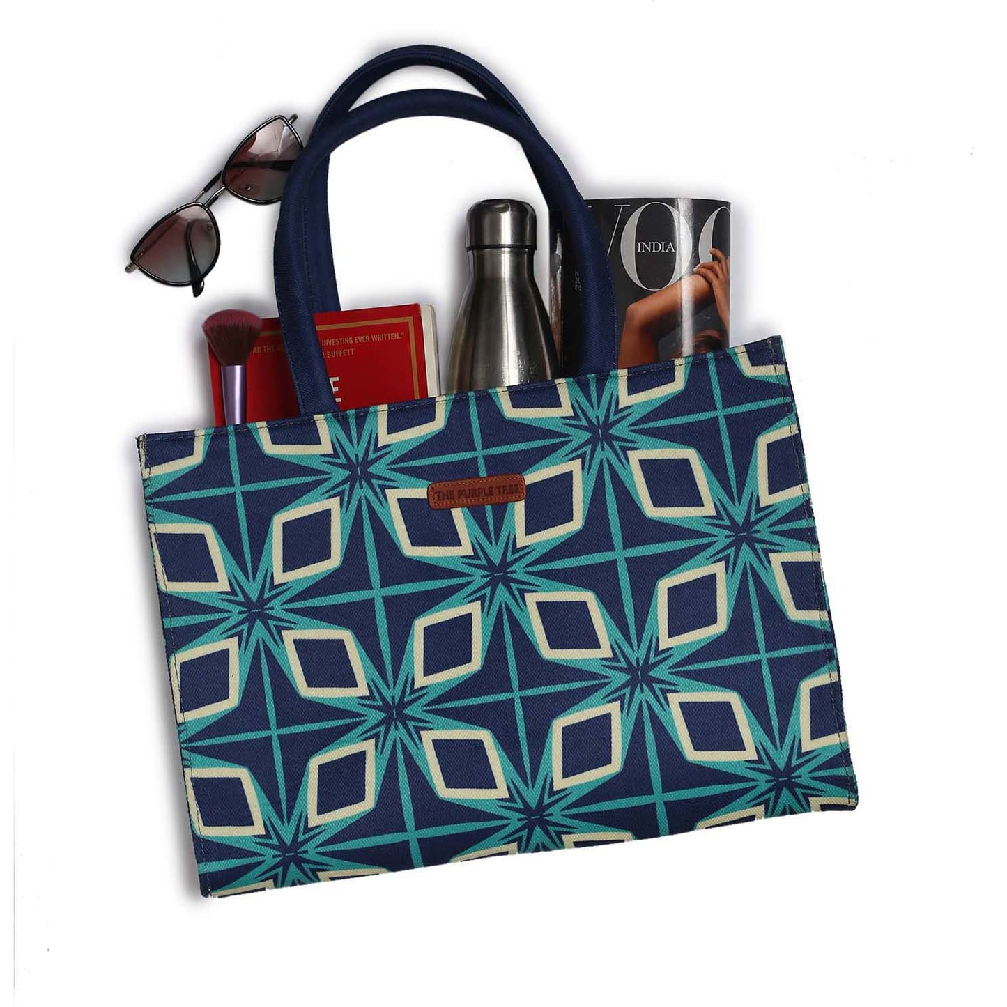An eye-catching tote bag adorned with a blue and green pattern, accompanied by a book and another book.