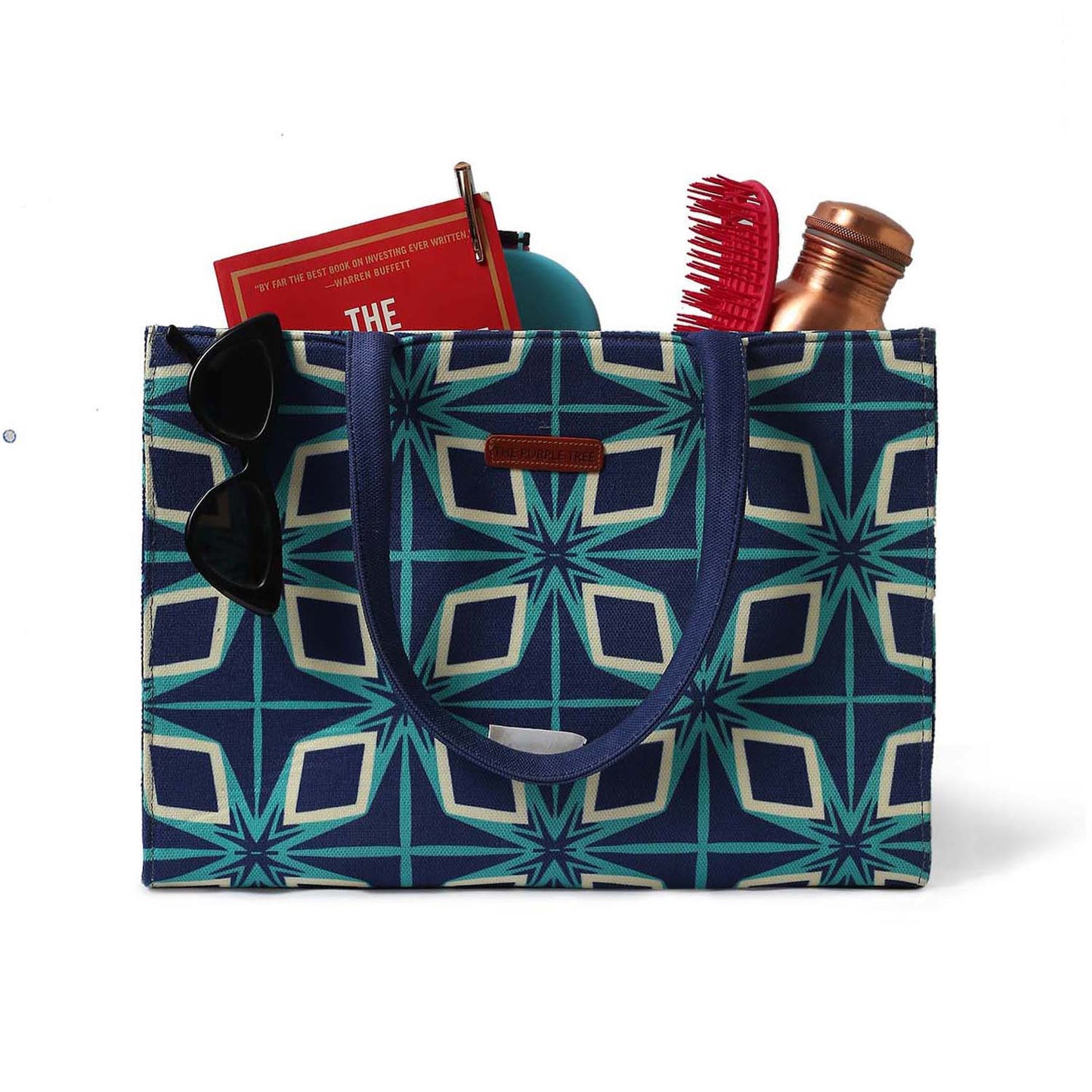 Trendy blue and green tote bag accessorized with book and sunglasses.
