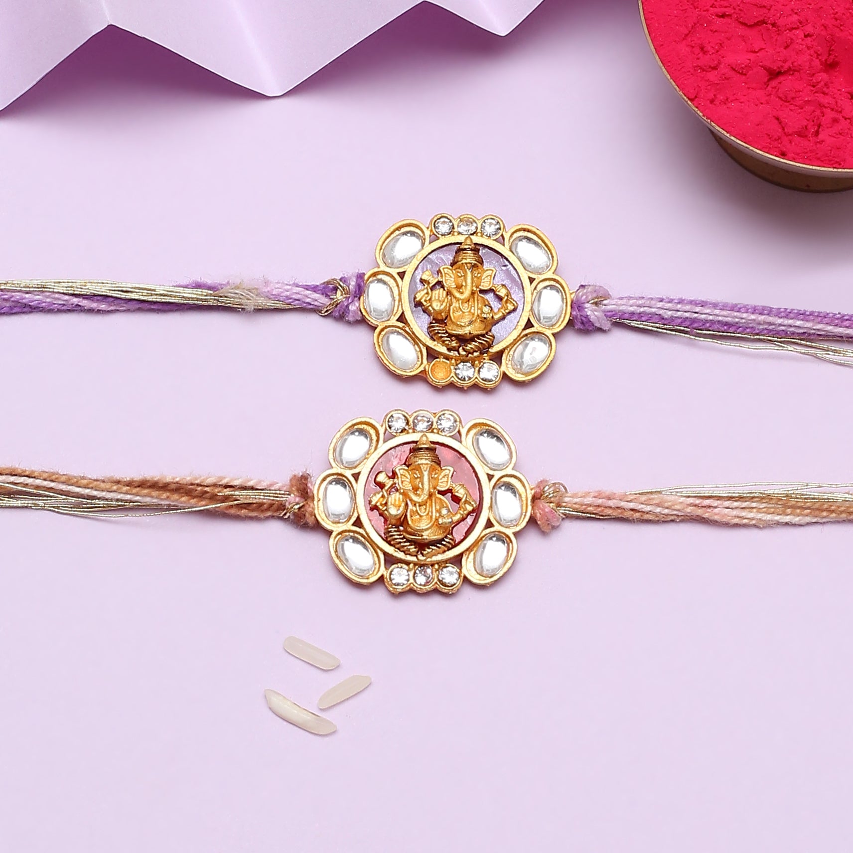 Two gold and purple rakhi with a flower, traditional Indian bracelets for celebrating Raksha Bandhan.