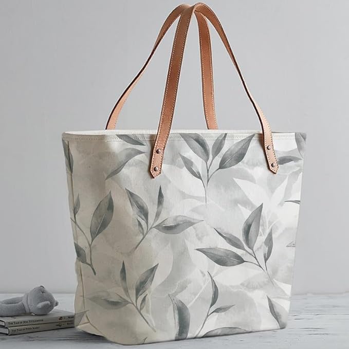 A fashionable tote bag showcasing a leaf print in white and gray hues.