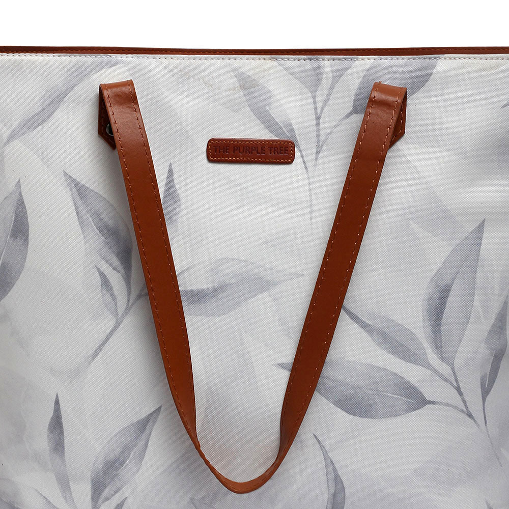 White and gray leaf print tote bag on a wooden table.