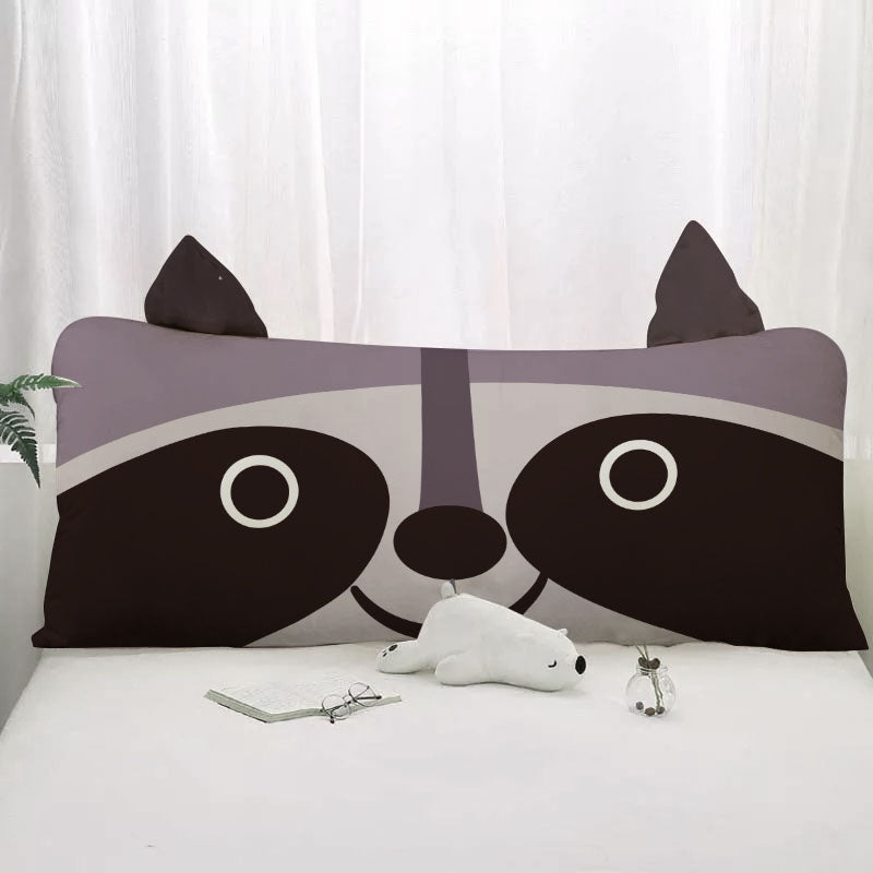 A pillow with a cute raccoon face, featuring its distinctive black mask and fluffy fur.