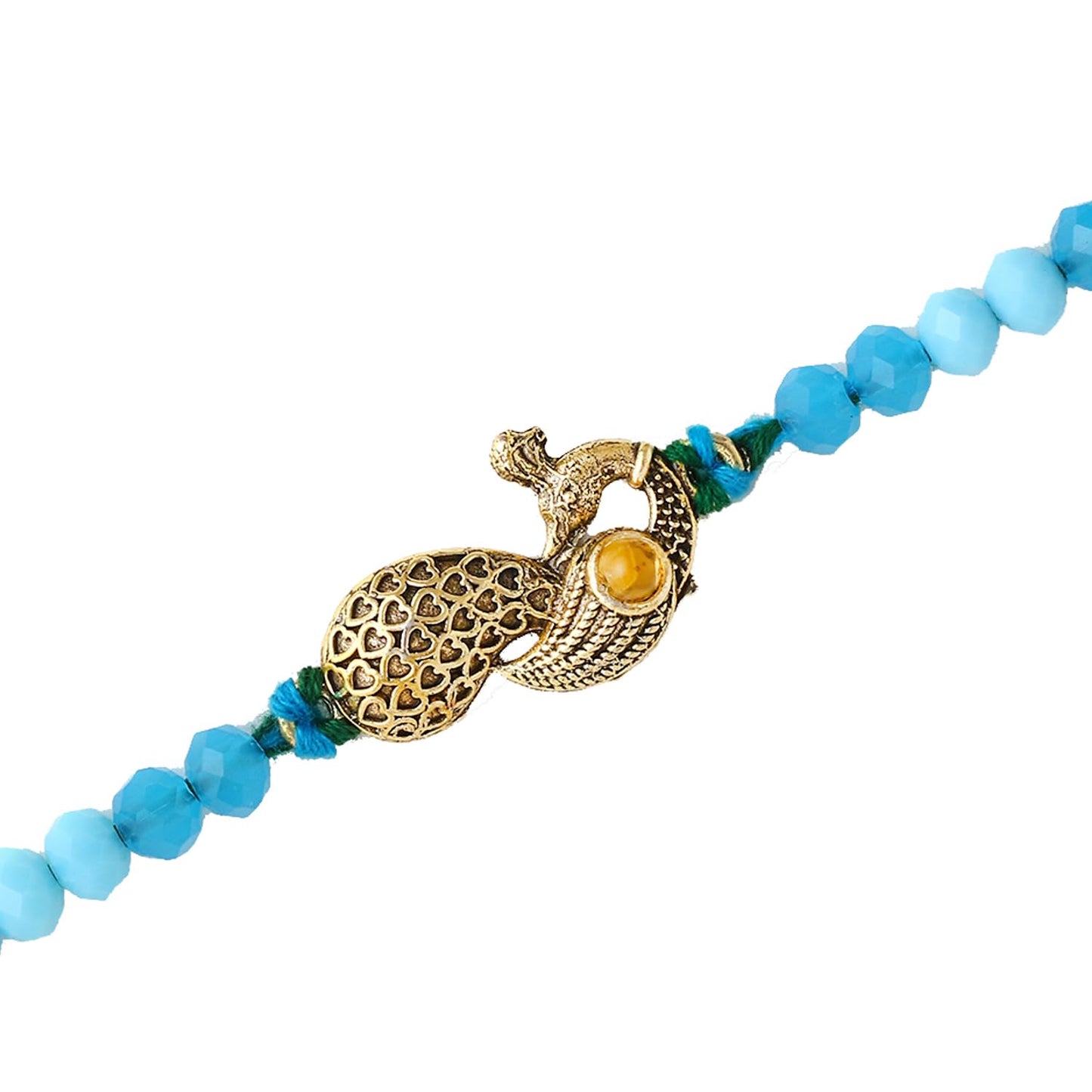 A charming peacock sits atop a rakhi, with a bowl of red powder nearby, showcasing a lovely festive arrangement on the table.