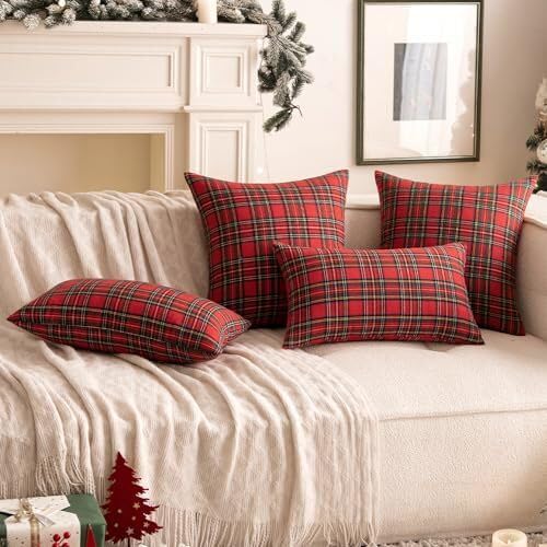 A pair of red plaid pillows on a couch are positioned next to a sparkling Christmas tree, enhancing the holiday spirit.