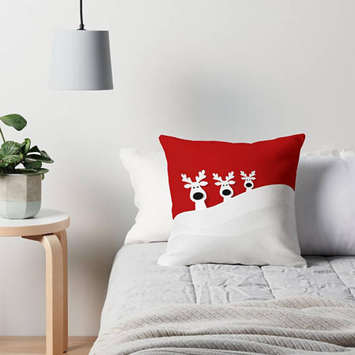 Festive scene with three reindeers on a red and white pillow.