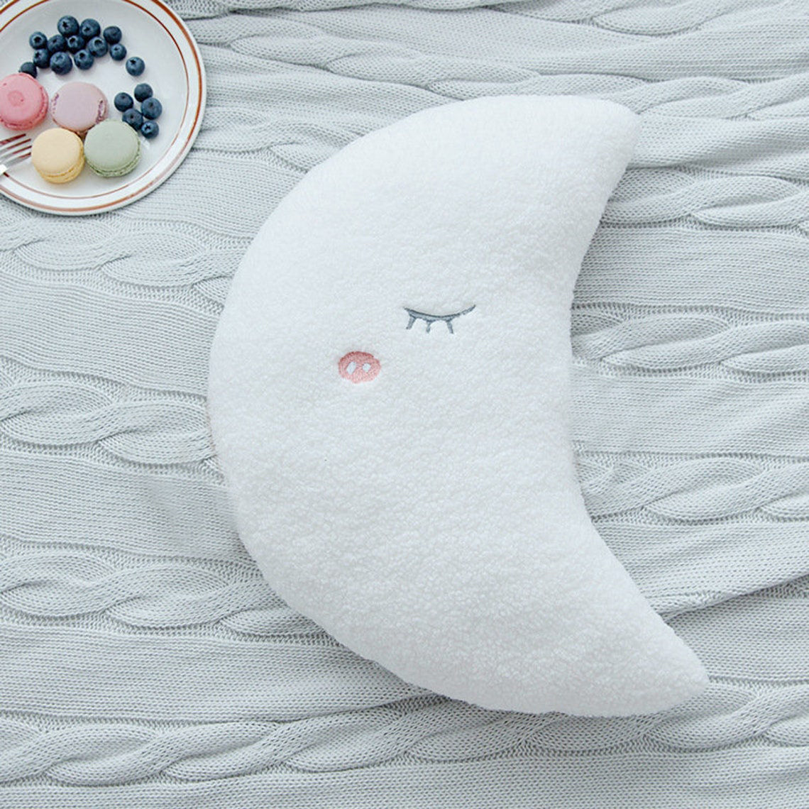 A plush toy wearing a crown rests on a bed, exuding a regal charm.