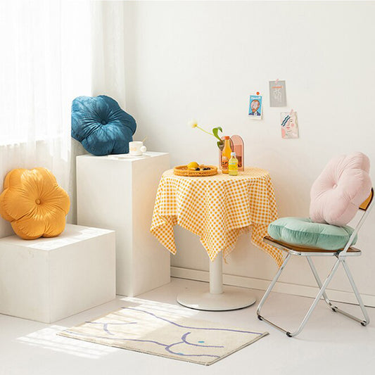 Pillows stacked on table next to yellow and blue checkered tablecloth.
