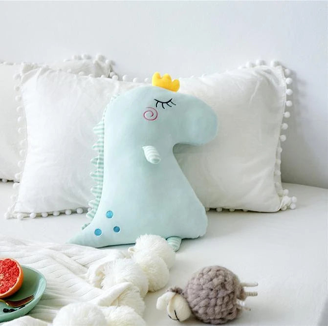 A plush toy wearing a crown rests on a bed, exuding a regal charm.