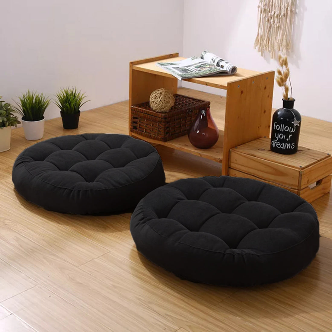 Two black round seat cushions on wooden flooring.