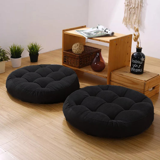 Two black round seat cushions on wooden flooring.