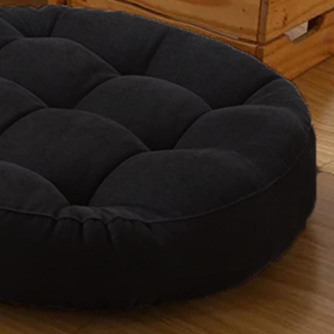 Two round black cushions on wooden floor.