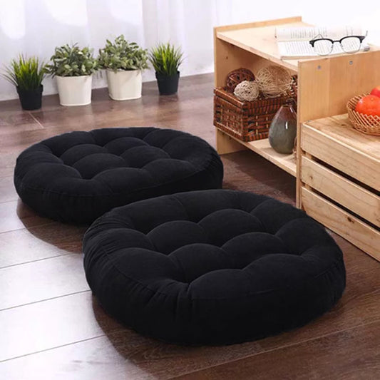 Two black cushions on wooden floor, creating cozy atmosphere in living room.