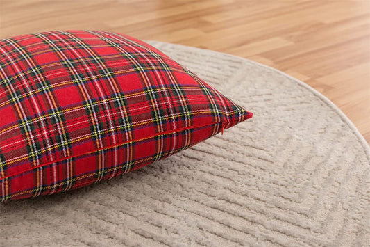 Plaid pillow in red and black on chair with plant.
