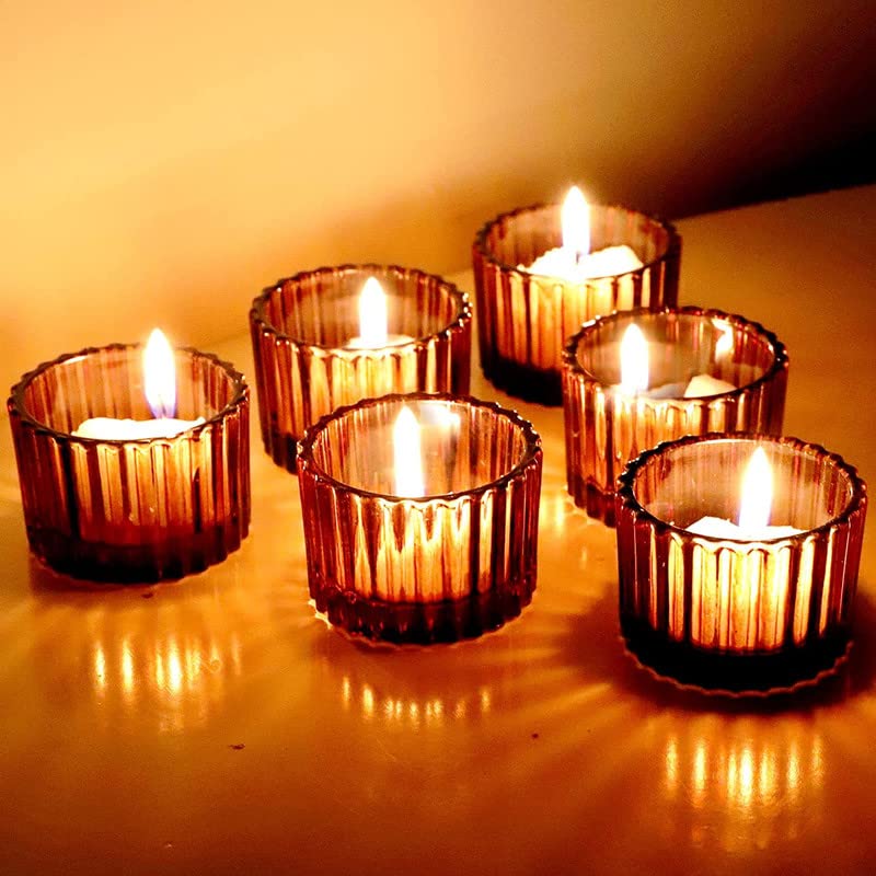 Glass cups holding six lit candles on a table