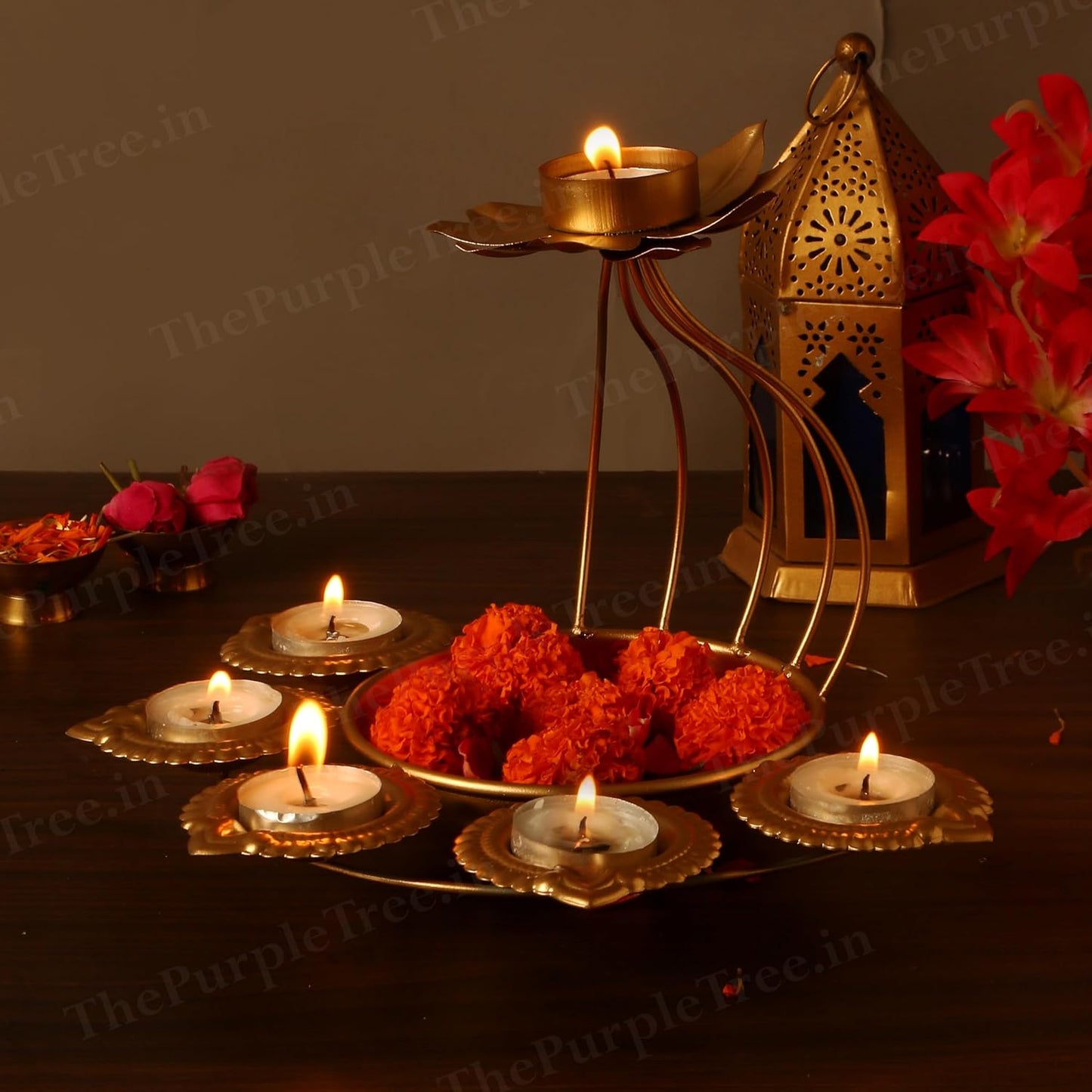 A table set with a gold candle holder, flowers, and candles.