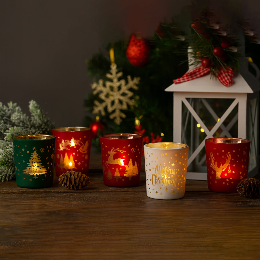 Set of Christmas-themed candle holders on a wooden surface with decorative background.
