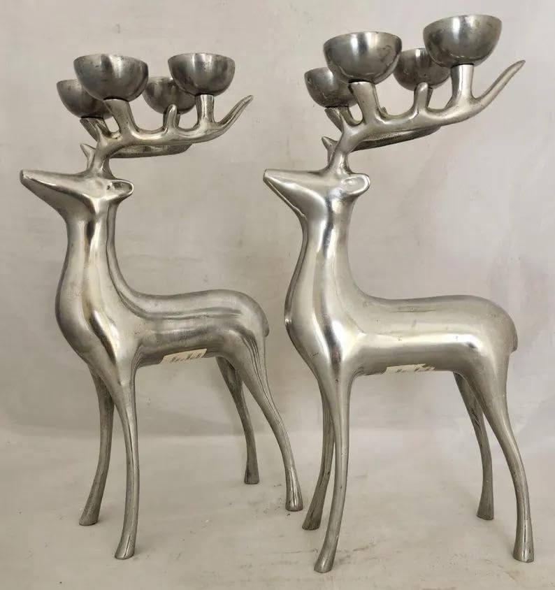 Two silver deer-shaped candle holders on a plain background