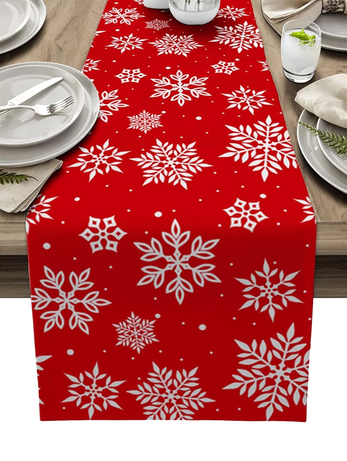 A table set with a vibrant red runner and a chair showcasing a charming white snowflake pattern.