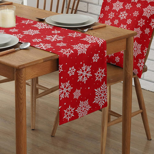 A table adorned with a red table runner, accompanied by a chair featuring a white snowflake pattern.