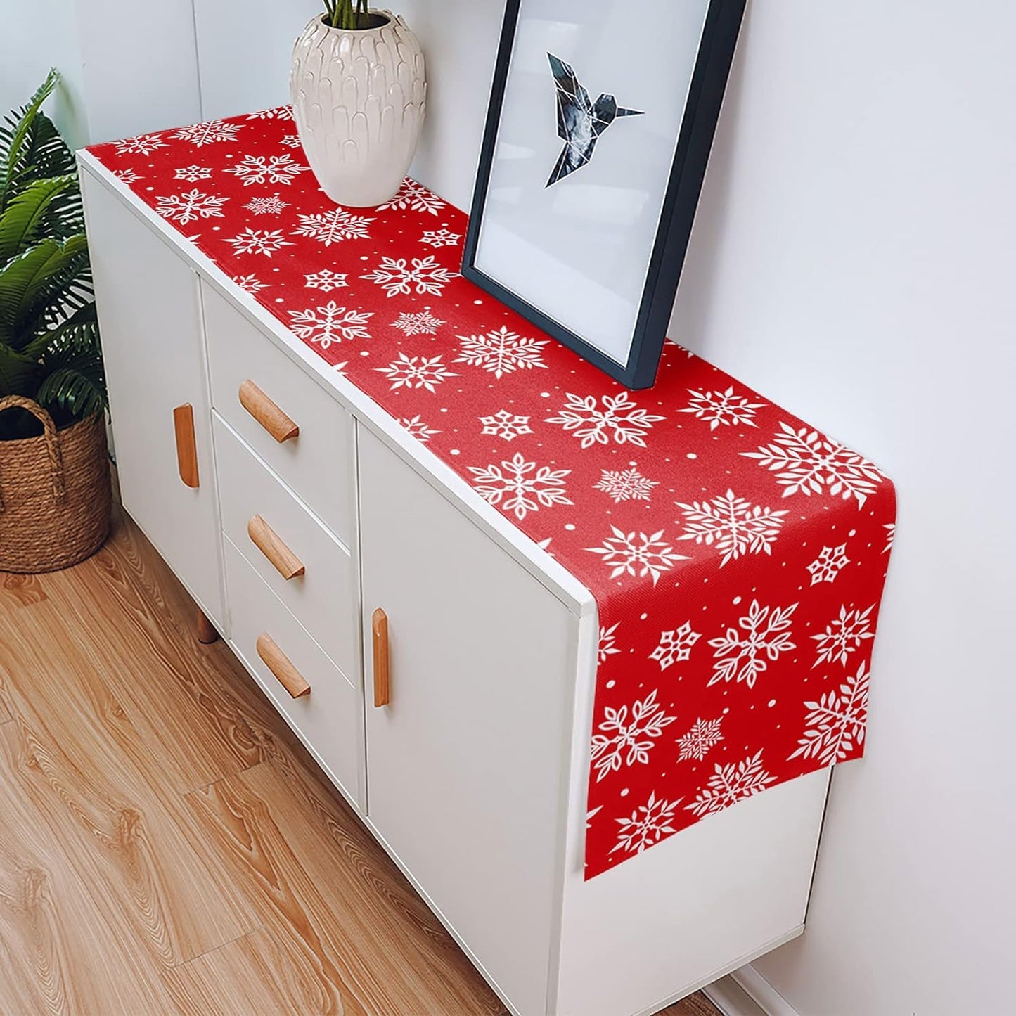 A table set with a vibrant red runner and a chair showcasing a charming white snowflake pattern.