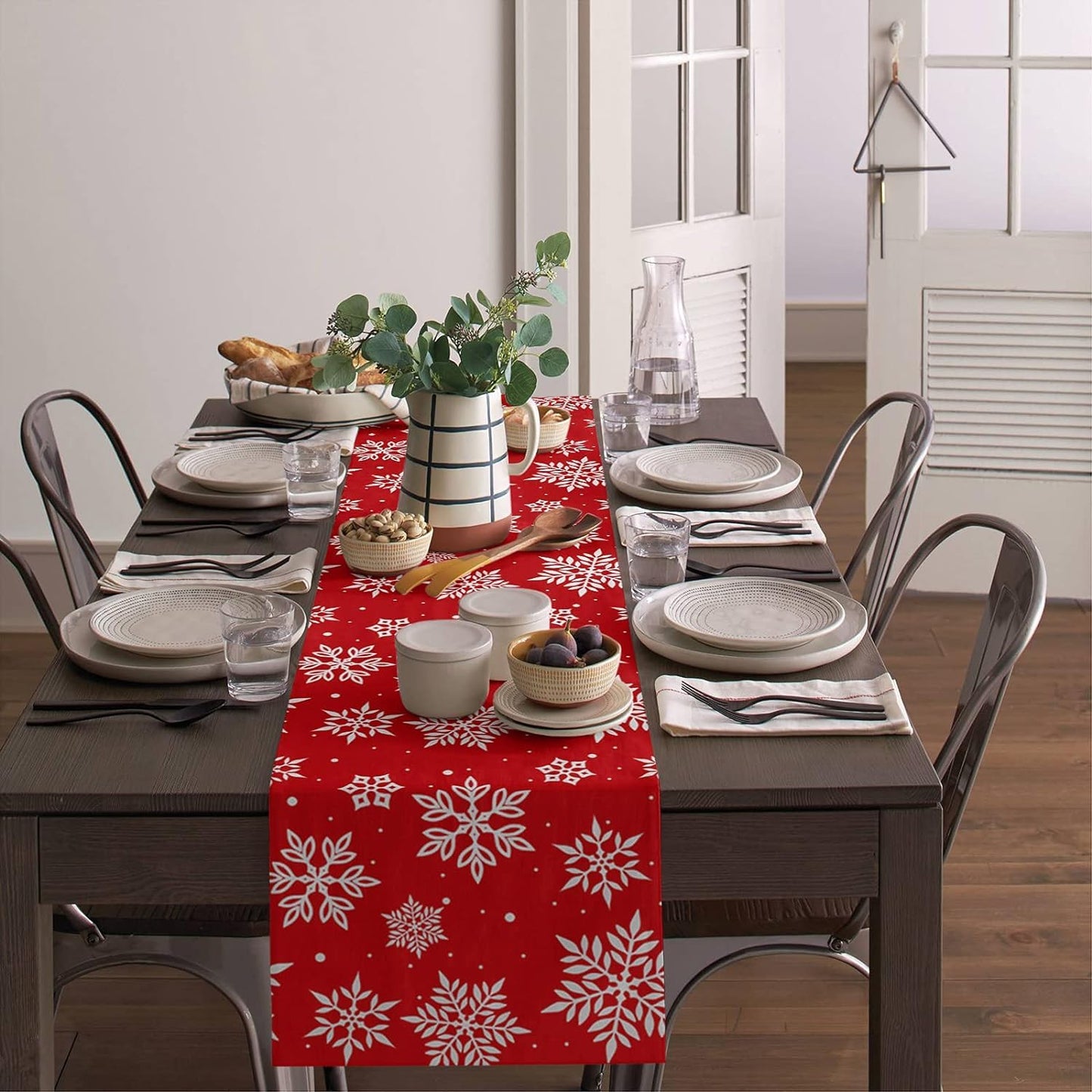 A red table runner on a table next to a chair decorated with a white snowflake motif.
