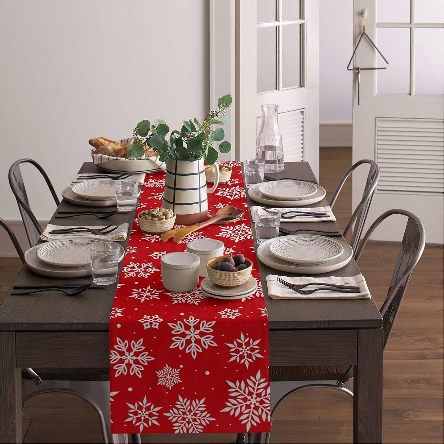 A red table runner on a table next to a chair decorated with a white snowflake motif.