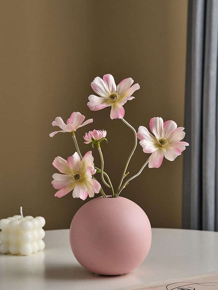 Pink vase with white flowers on table.