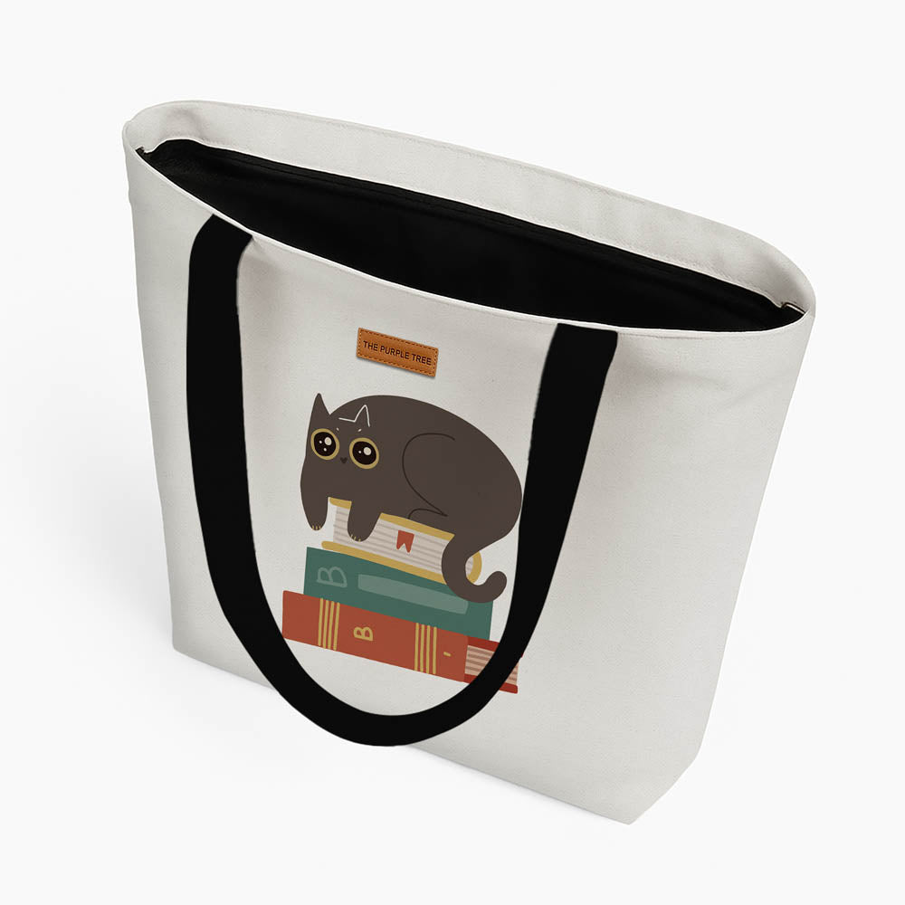 A tote bag displaying a cat resting on a stack of books, symbolizing a blend of literature and pet affection.