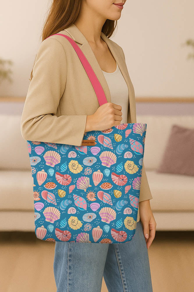 A blue tote bag featuring an array of colorful shells printed on its surface.