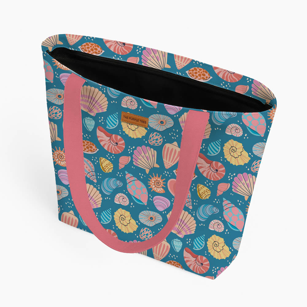 A blue tote bag decorated with various bright shells, showcasing a playful design.