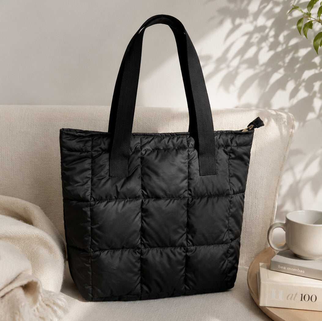 Black puffer tote bag on a light-colored sofa with a neutral background