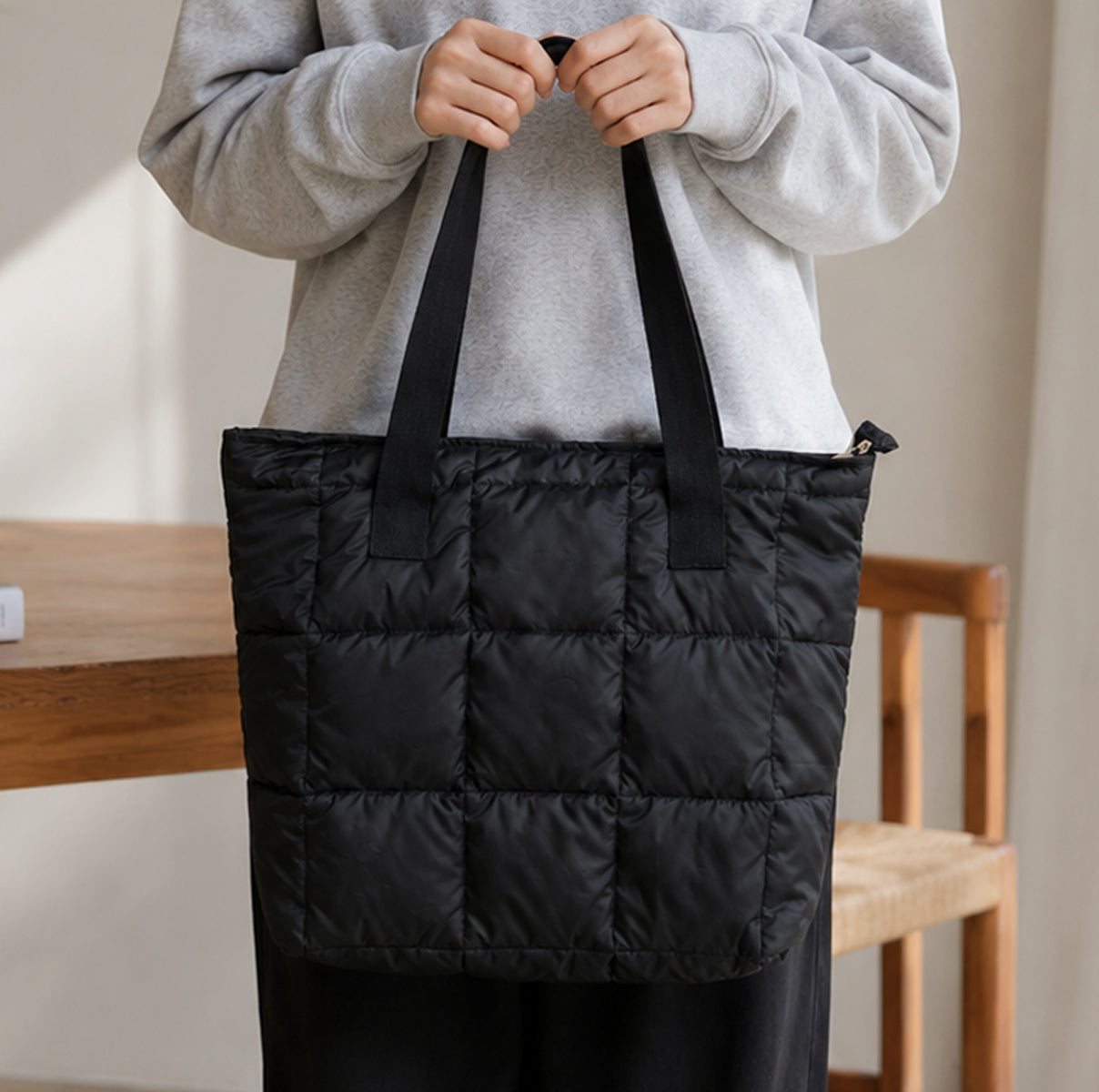 Person holding a black puffer bag indoors
