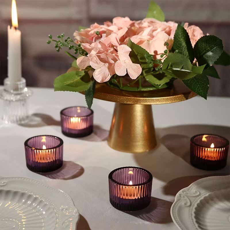 Decorative table setting with pink flowers, candles, and a gold stand.