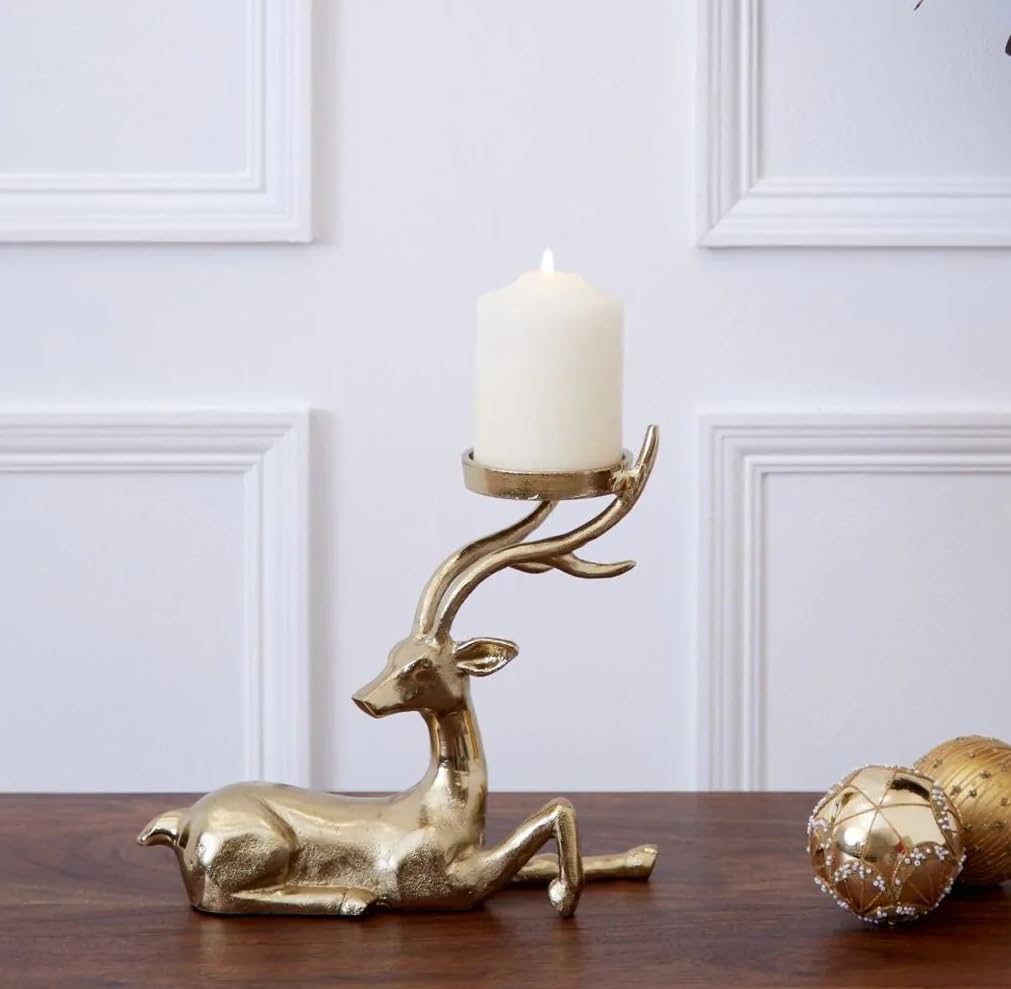 Gold deer-shaped candle holder with a lit candle on a wooden surface, Christmas tree and decorations in the background.
