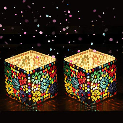 Two colorful mosaic candle holders on a dark background with confetti.