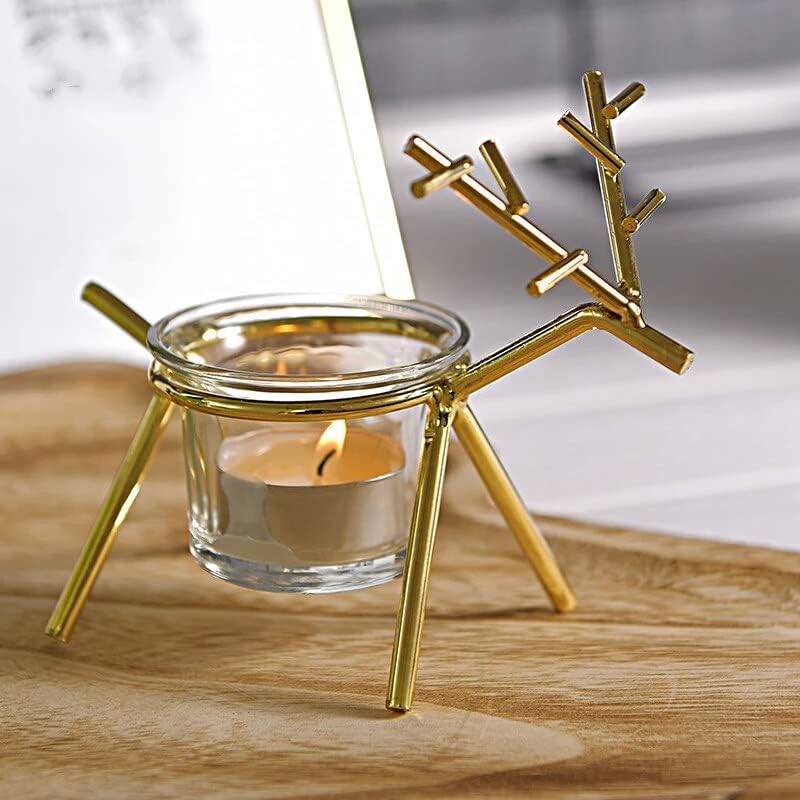 Gold reindeer-shaped candle holder with a lit candle inside on a wooden surface.