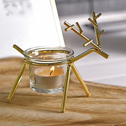 Gold reindeer-shaped candle holder with a lit candle inside on a wooden surface.