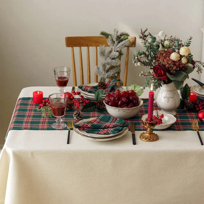 A beautifully arranged table featuring a Christmas tree and a vibrant red and green plaid tablecloth, perfect for the holidays.