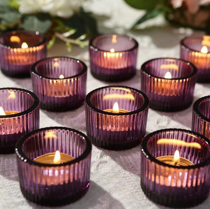 Purple candle holders with lit candles on a textured surface