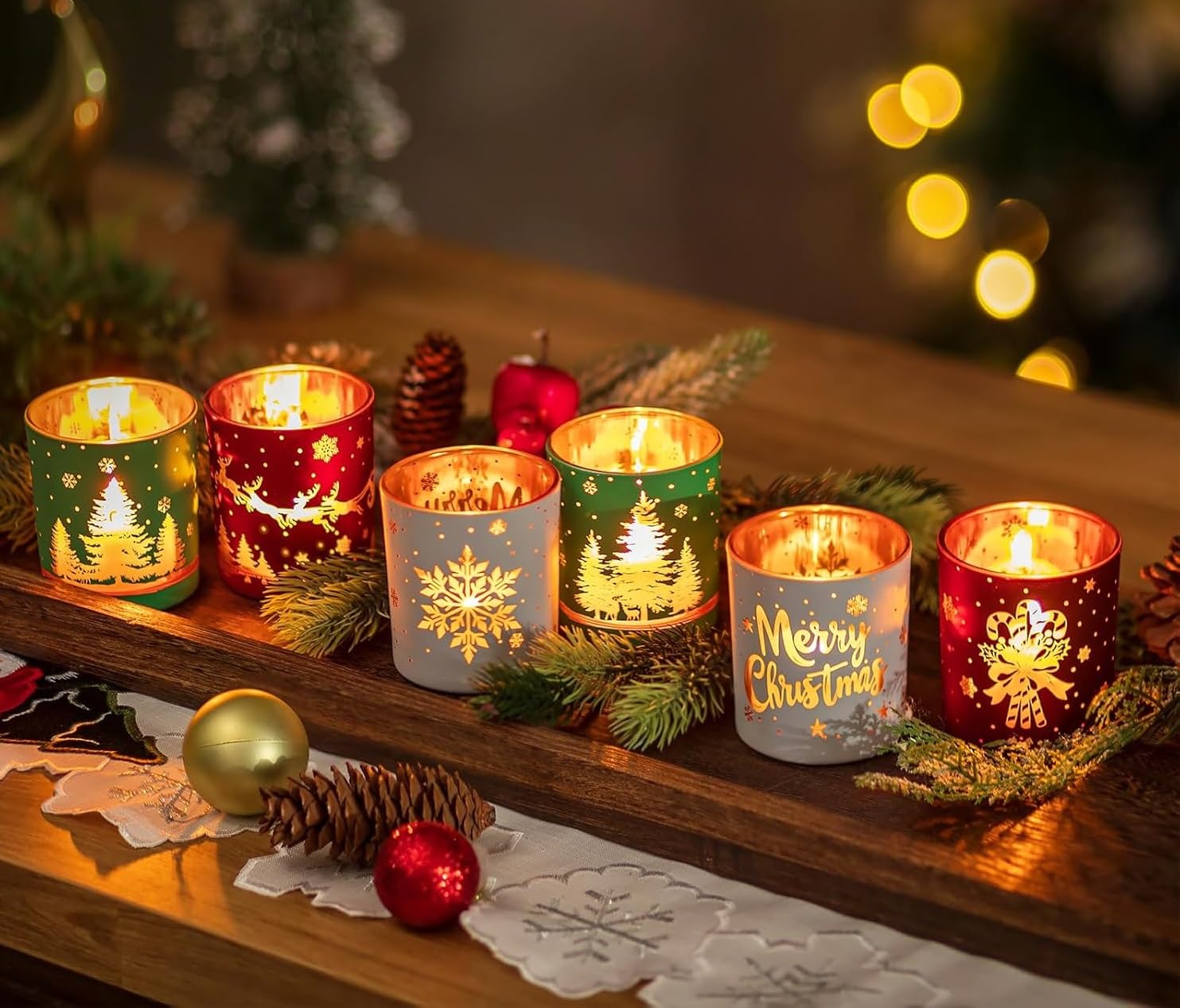 Decorative candles in festive holders on a wooden surface with Christmas decorations.