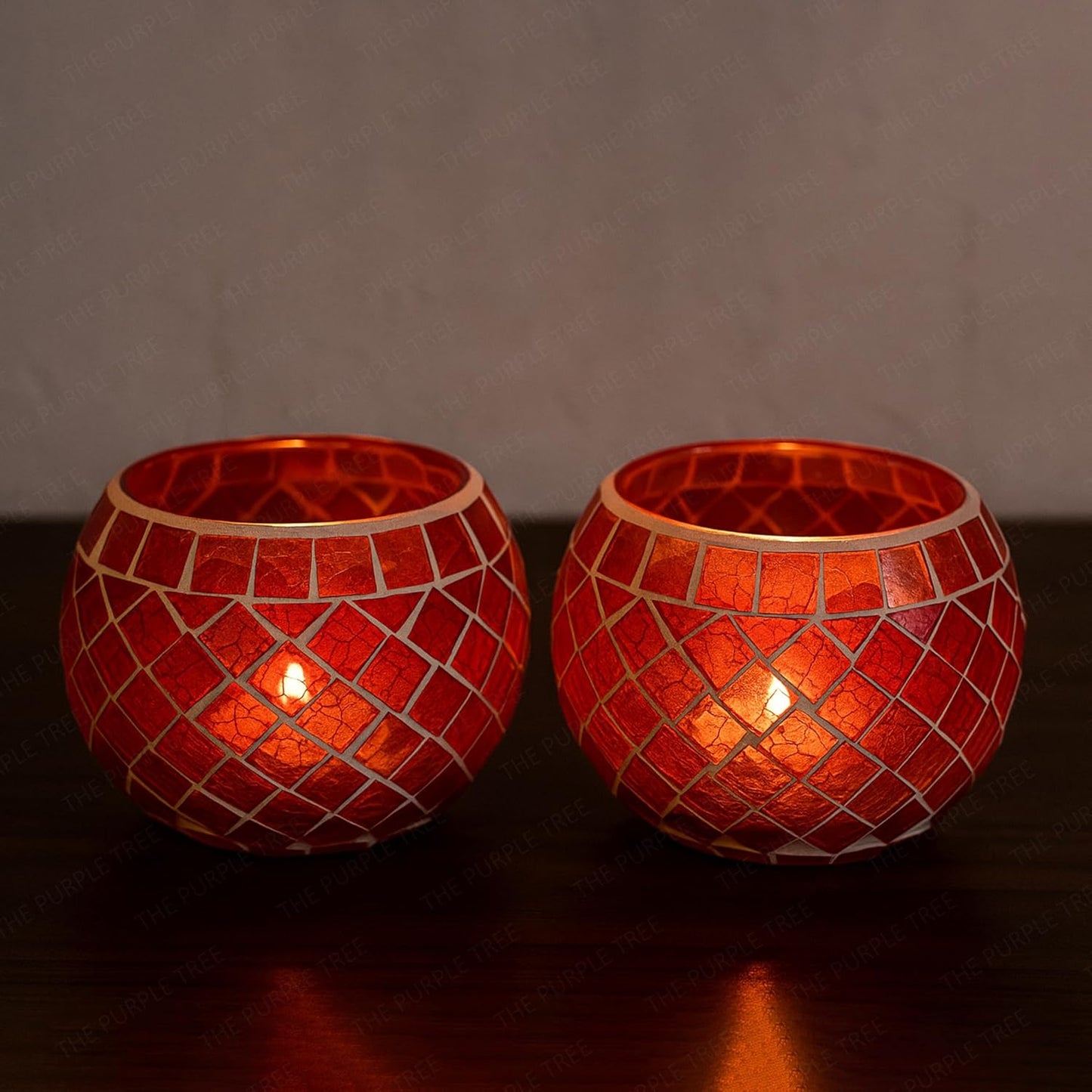 Two red glass tealights glowing on a table