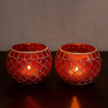 Two red glass tealights glowing on a table