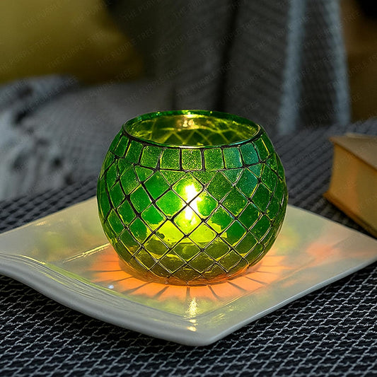 Green mosaic candle holder on a white plate with a blurred background