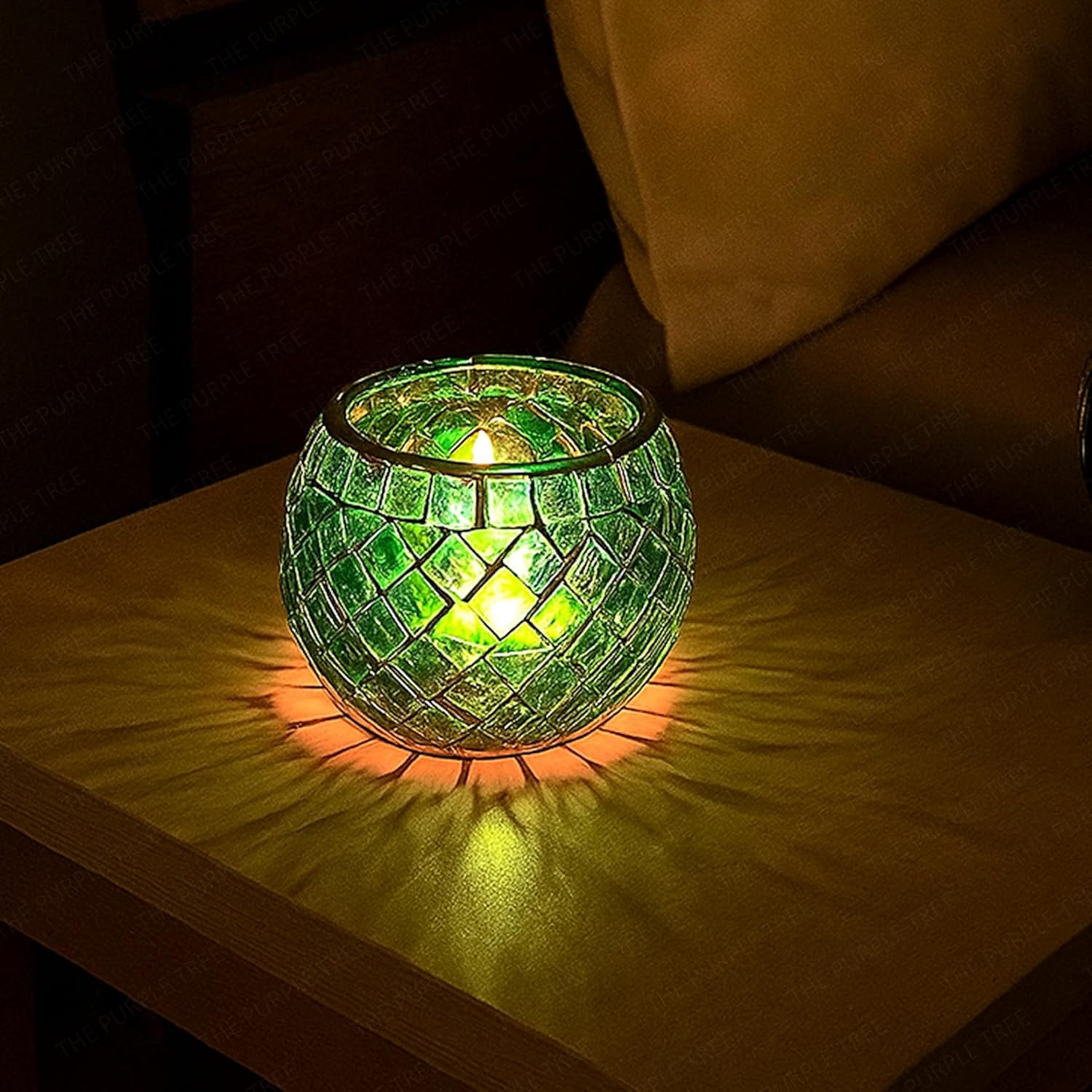 Green mosaic candle holder on a white plate with a blurred background